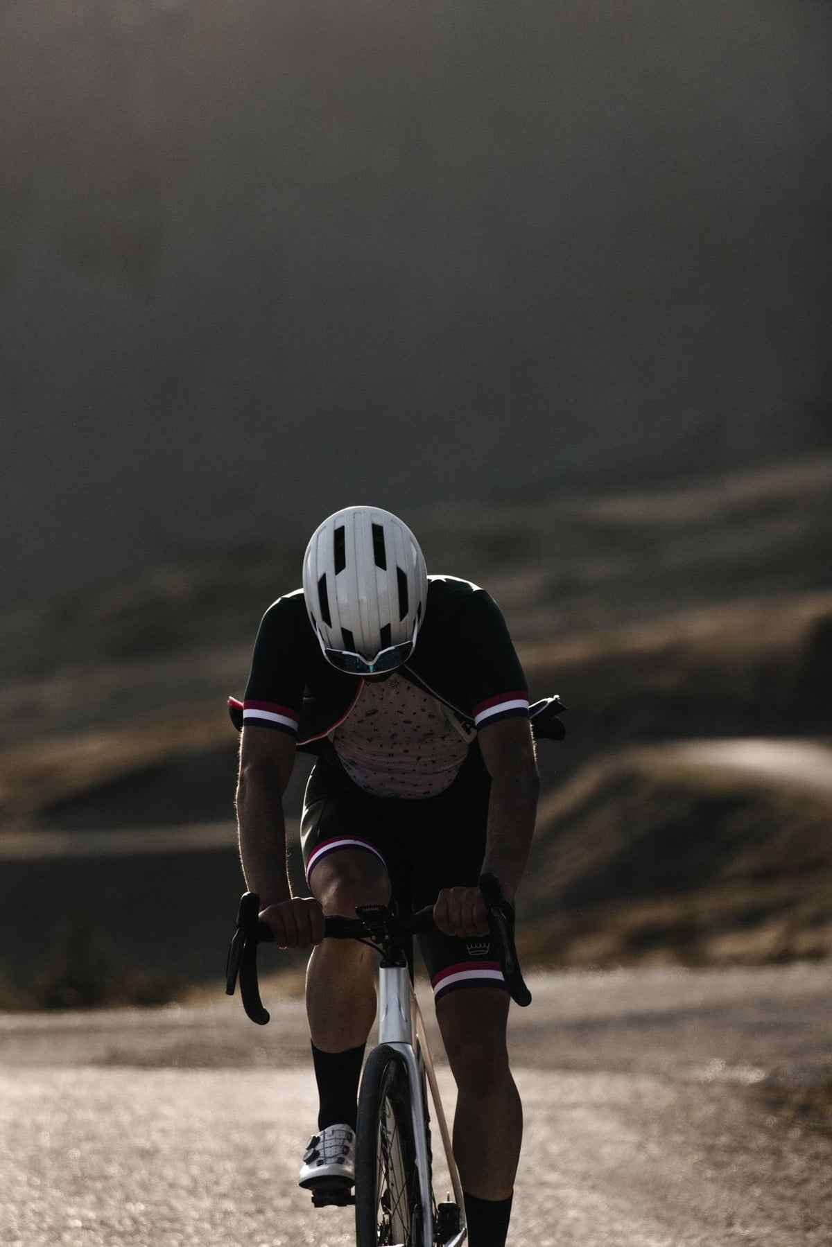Profile of a cyclist in a green Saint-Étienne jersey, mountains in the background